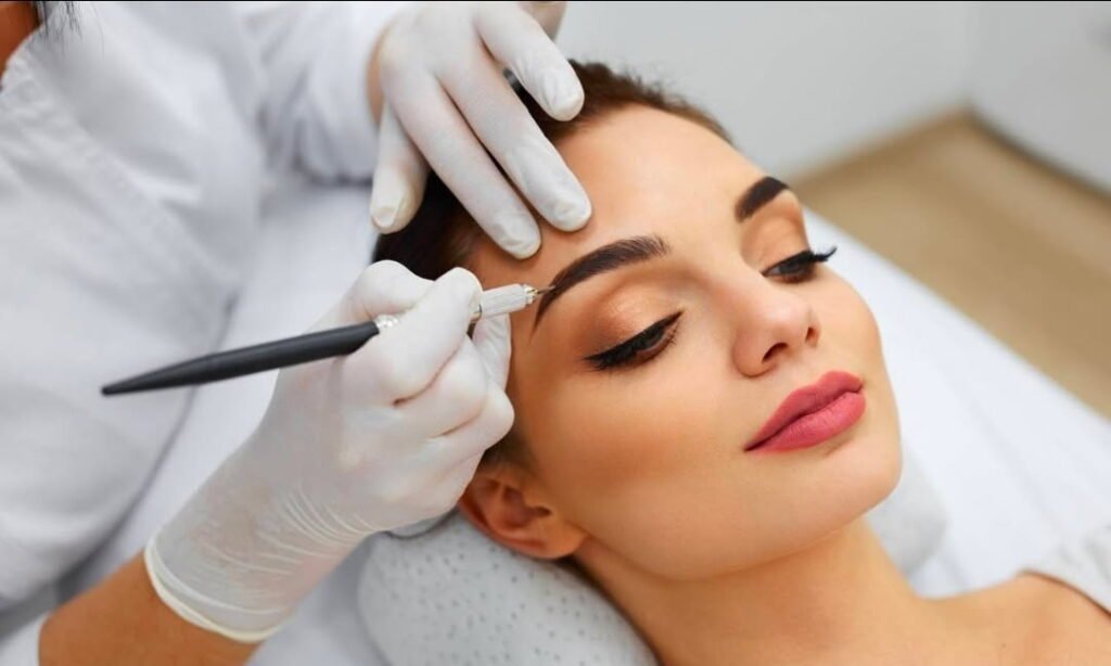 Close-up of a professional brow treatment being performed with precision tools by a licensed technician in a clean, luxury beauty setting.